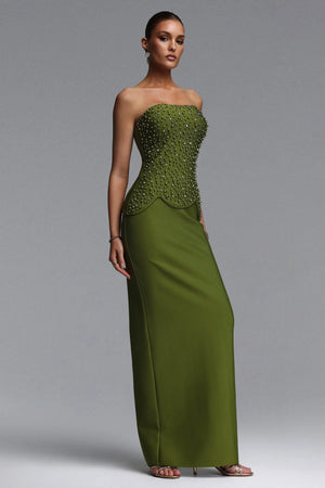 Woman wearing a strapless green evening gown with beaded top on a gray background