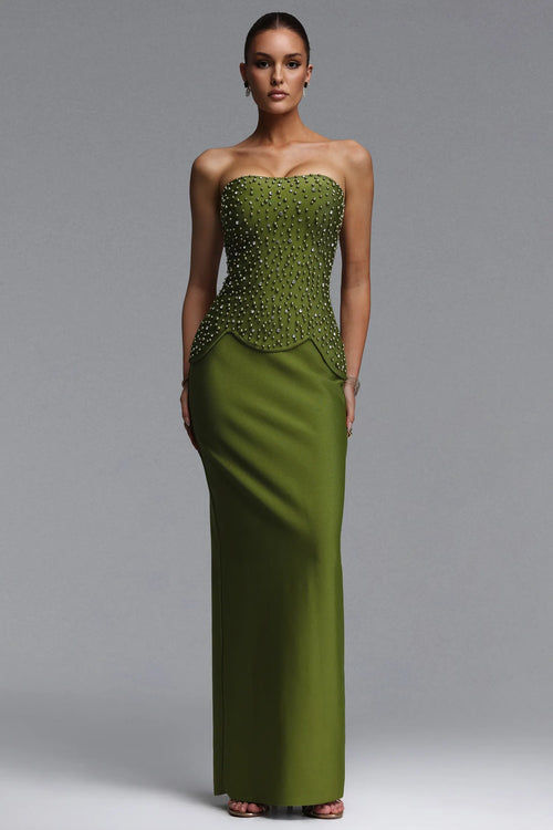 Woman wearing a green strapless gown with beaded detailing on a gray background