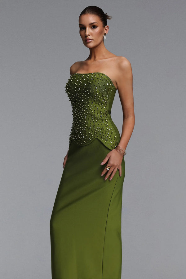 Woman wearing a green strapless gown with beaded top on a gray background