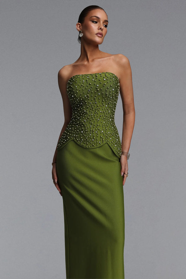 Woman wearing a strapless green evening gown with beaded top on a gray background