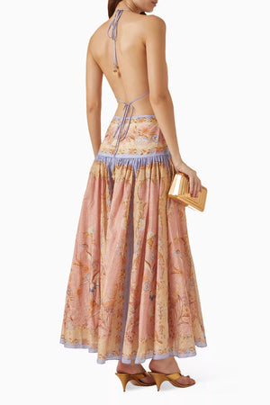 Woman wearing a floral dress with a backless design, holding a small bag.