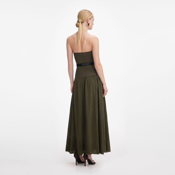 Woman wearing a long green dress with a black belt on a white background