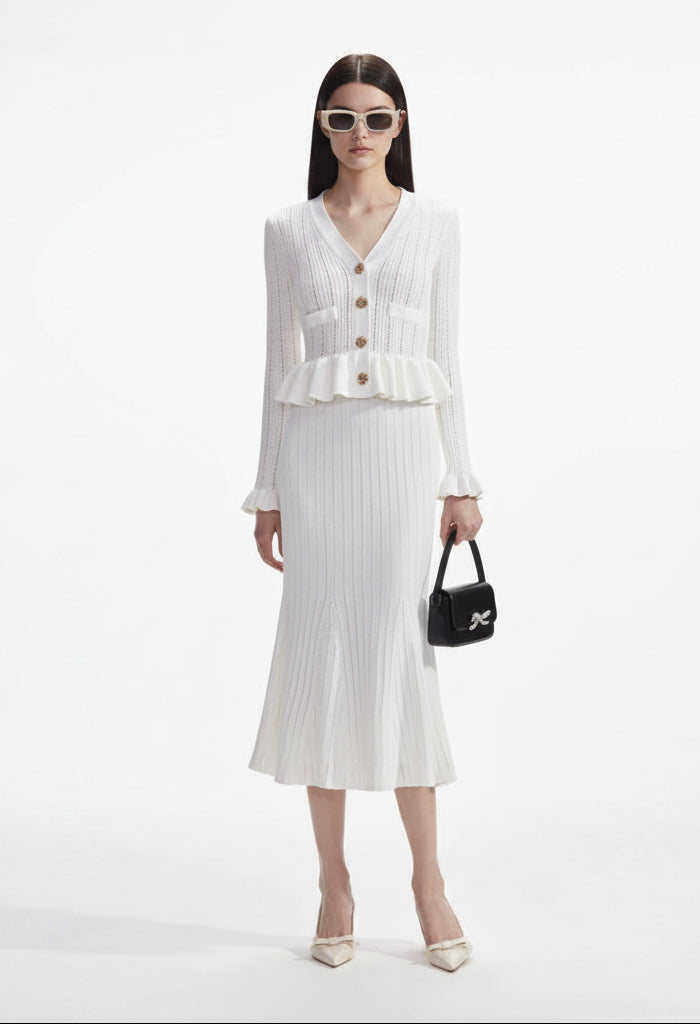 Woman wearing a white outfit with a black handbag on a white background