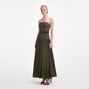 Woman wearing a strapless green dress with a belt on a white background