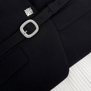 Black coat with decorative silver buckle and earring on a white background