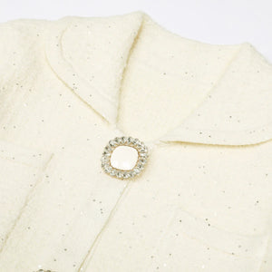 Close-up of a textured beige fabric with a decorative brooch featuring a circular design and small stones.