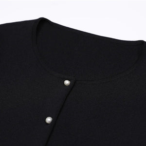 Close-up of a black garment with white buttons on a light gray background