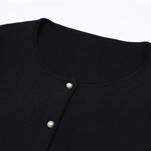 Close-up of a black garment with white buttons on a light gray background