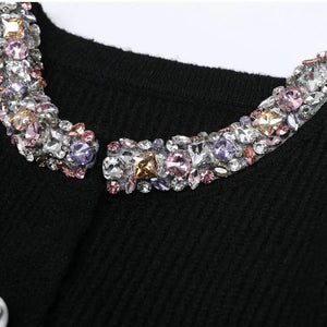 Black sweater with a decorative multicolored gemstone collar on a white background