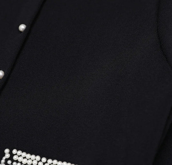 Close-up of a black garment with pearl buttons and trim