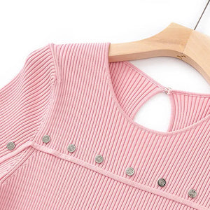 Pink ribbed sweater with button details on a wooden hanger against a white background