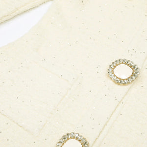 Close-up of gold earrings with gemstones on a textured beige surface