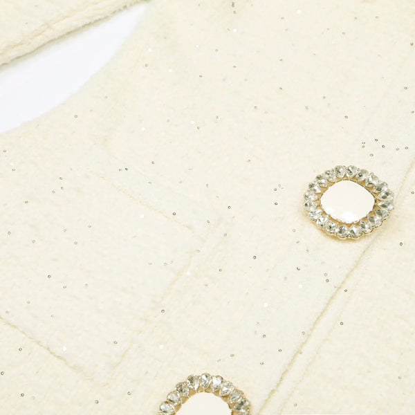 Close-up of gold earrings with gemstones on a textured beige surface