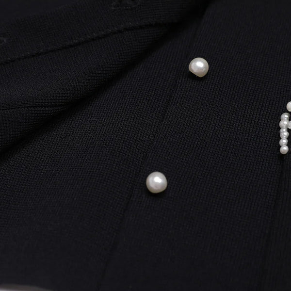 Close-up of a black garment with pearl buttons and embellishments.