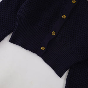 Navy blue cardigan with gold buttons on a white background