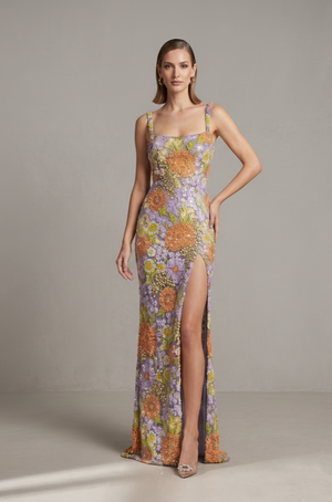 Woman wearing a floral dress with a slit on a plain background