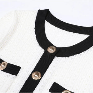 Close-up of a white garment with black collar and gold buttons on a light gray background