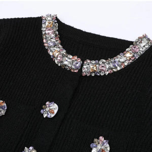 Black sweater with decorative crystal collar and buttons on a white background