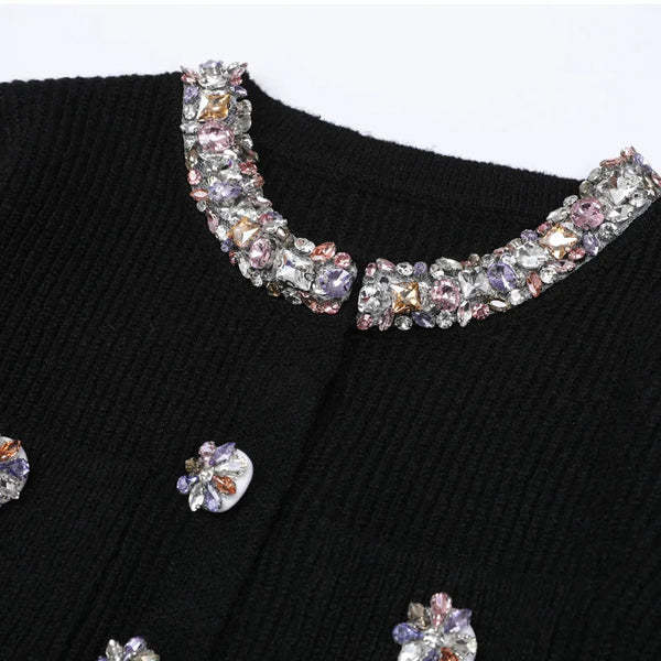 Black sweater with decorative crystal collar and buttons on a white background