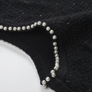 Black garment with pearl embellishments on a white background
