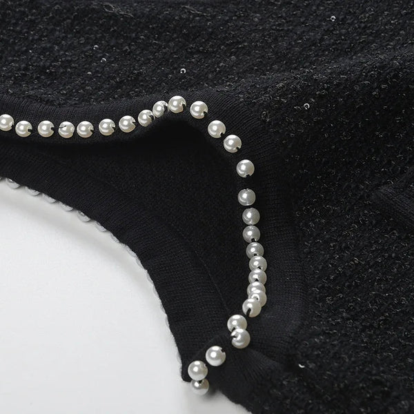 Black garment with pearl embellishments on a white background