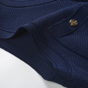 Folded navy blue garment with a gold button on a light gray background