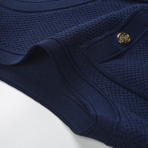 Folded navy blue garment with a gold button on a light gray background