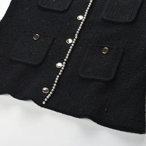 Close-up of a black coat with button details on a white background
