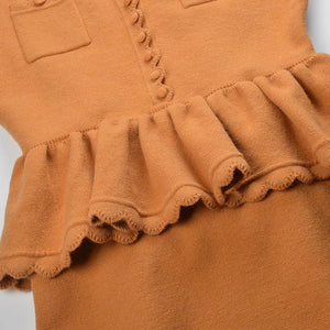 Close-up of a brown dress with ruffled details on a white background