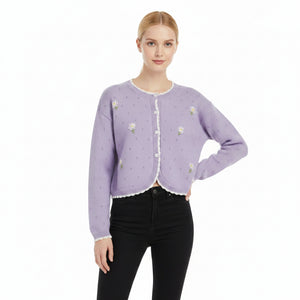 Woman wearing a light purple cardigan with floral embellishments on a white background