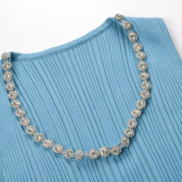Blue ribbed sweater with a decorative silver necklace on a white background