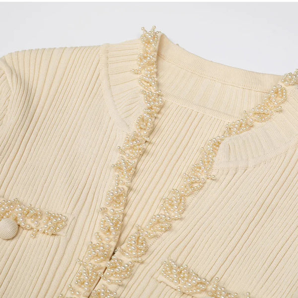 Beige knitted cardigan with decorative trim on a light gray background