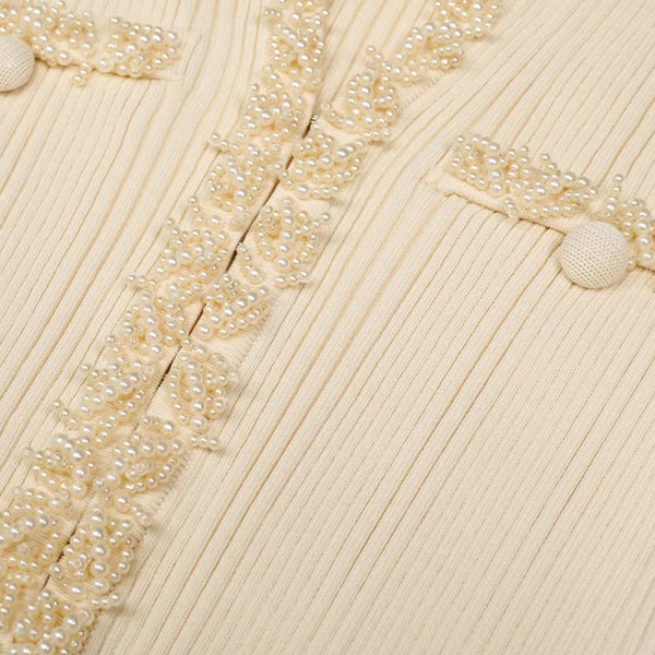Close-up of a ribbed fabric with decorative bead trim on a beige background