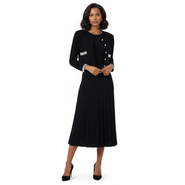 A woman modeling a black long-sleeve midi dress with a pleated skirt, featuring silver button details on the front and silver trim on the cuffs, paired with black high heels against a plain white background.