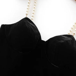 Black top with pearl straps on a wooden hanger against a white background