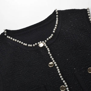 Black garment with silver beaded details on a white background
