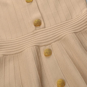 Close-up of a beige dress with gold buttons on a light gray background
