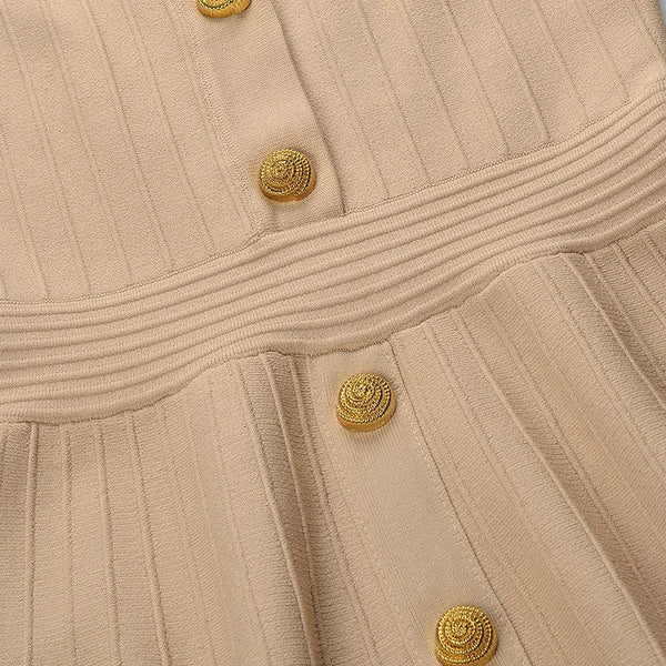 Close-up of a beige dress with gold buttons on a light gray background