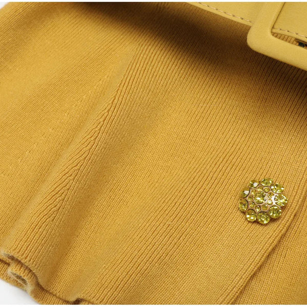 Close-up of a mustard yellow fabric with a decorative button on a white background