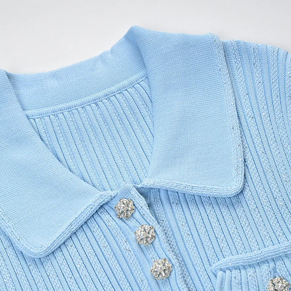 Close-up of a light blue sweater with a collar and decorative buttons on a white background