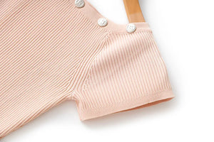 Close-up of a pink ribbed baby romper with buttons on a white background