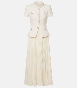 An off-white two-piece set featuring a short-sleeve cropped jacket with decorative silver-tone buttons and a matching pleated maxi skirt, shown against a plain light gray background.