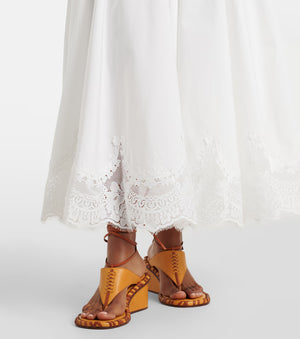 Yellow sandals worn with white lace pants on a white background
