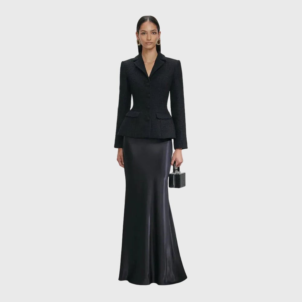 Woman wearing a black suit with a long black skirt on a white background