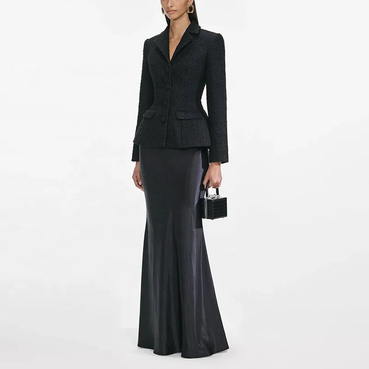 Woman wearing a black suit with a long black skirt on a white background